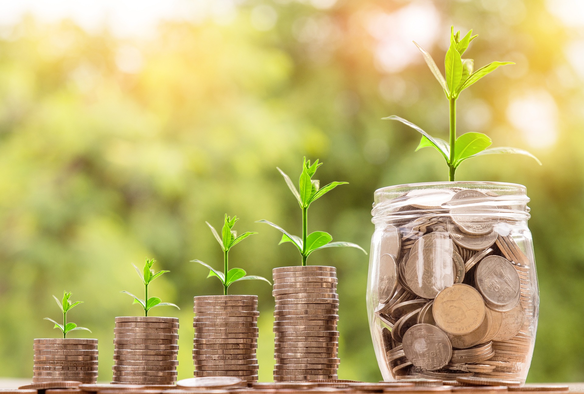 stacked coins and coin jar with plants growing out of them.